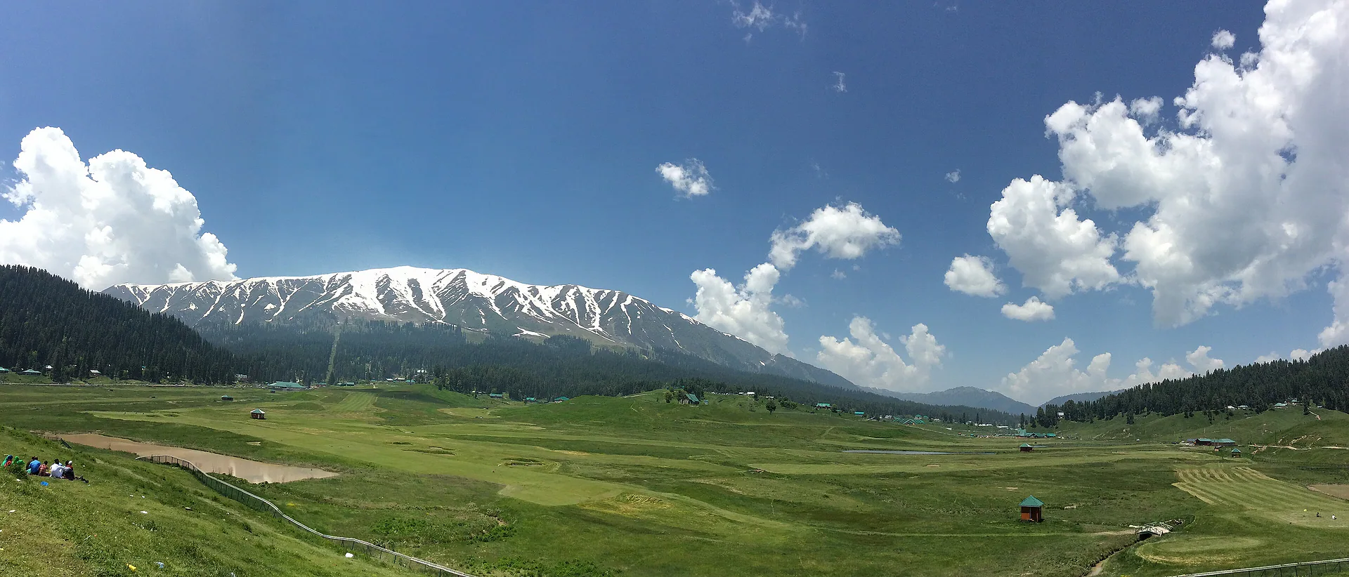 The wide green meadows of Gulmarg beneath snowy ridges