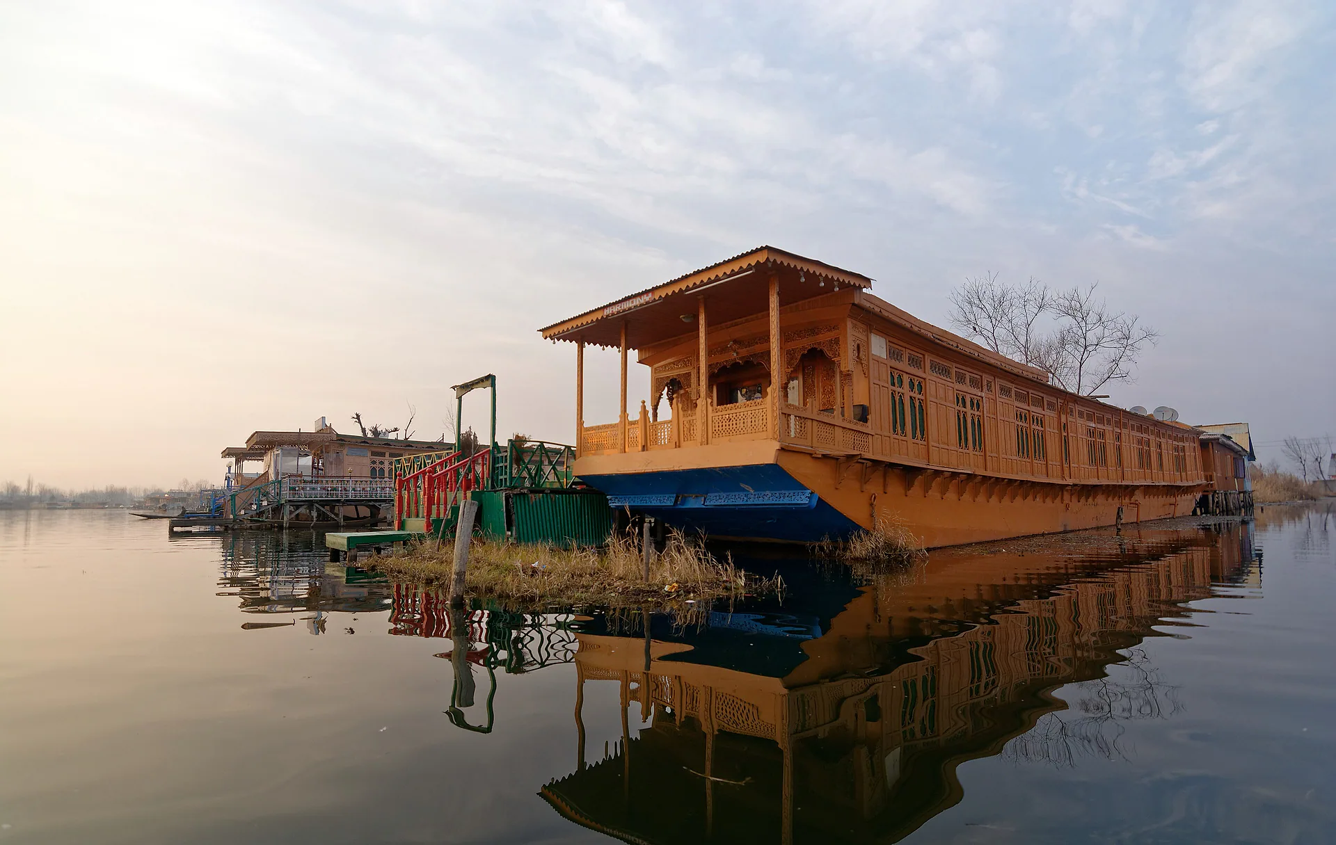 A carved wooden houseboat reflected in the still water of Dal Lake
