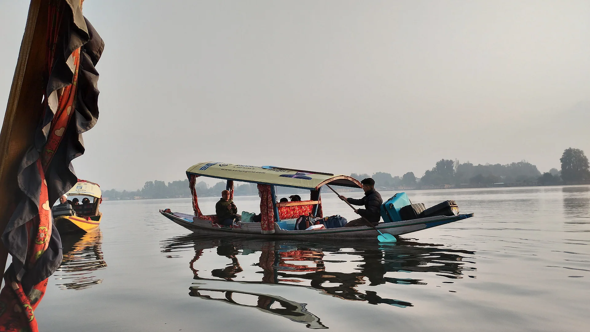 A shikara moving across Nigeen Lake in morning haze